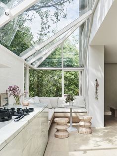 a kitchen with white walls and flooring next to a large glass window that overlooks trees