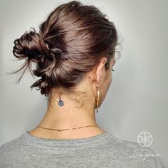 a woman with a tattoo on her neck is wearing a gray shirt and gold earrings