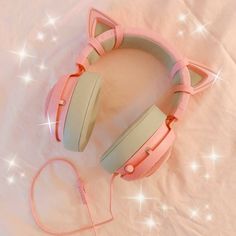 a pair of pink headphones laying on top of a white sheet with stars in the background