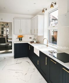 a kitchen with marble counter tops and black cabinets, gold pulls on the faucets