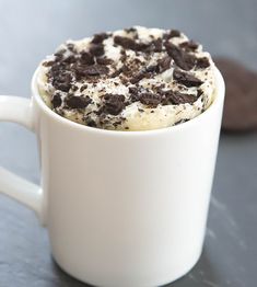 a white cup filled with whipped cream and chocolate chips on top of a gray table