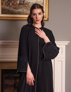 Step into timeless elegance with this exquisite black abaya, perfect for any special occasion or everyday wear. The abaya features beautifully embellished cuffs adorned with intricate beading that adds a touch of sophistication to the classic design. Crafted from high-quality fabric, this abaya drapes gracefully, providing both comfort and style. The subtle beading along the centerline further enhances the abaya's refined look, making it a must-have addition to any modest wardrobe. Whether you'r Fitted Black Abaya For Eid, Elegant Festive Abaya, Evening Embellished Black Abaya, Formal Fitted Black Abaya, Black Embellished Evening Abaya, Evening Black Embellished Abaya, Elegant Fitted Black Abaya, Luxury Long Abaya For Formal Occasions, Elegant Black Abaya For Formal Occasions