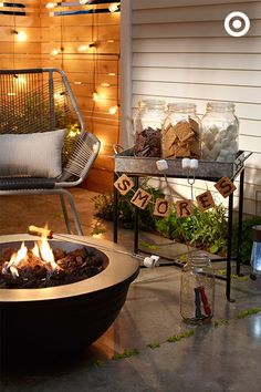 a fire pit sitting in the middle of a patio next to a chair and table