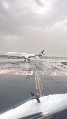 an airplane that is sitting on the tarmac in the rain, with it's landing gear down