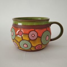 a green and brown coffee cup sitting on top of a white table