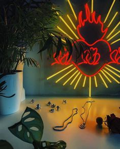 a neon sign that says love is surrounded by other jewelry and plants in front of it