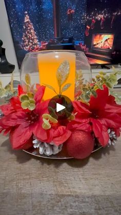 a glass bowl filled with poinsettia and oranges on top of a table