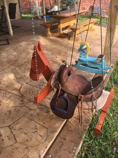 a brown horse saddle sitting on top of a wooden swing