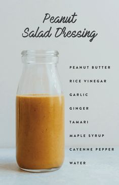 the ingredients for peanut salad dressing in a glass jar on a white surface with black writing