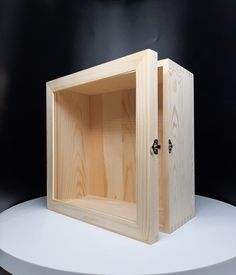 an empty wooden box sitting on top of a white table next to a black wall