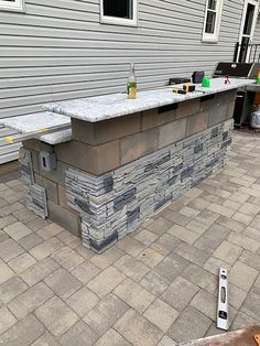 an outdoor bar is built into the side of a house with brick pavers around it