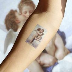 a small tattoo on the arm of a woman with an angel and cherub design