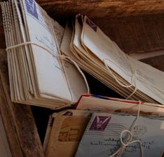 several envelopes are piled on top of each other in an old wooden box and tied with twine