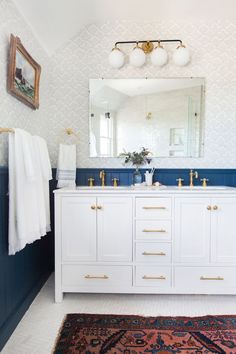 the bathroom is decorated in blue and white with gold accents on the vanity, along with two mirrors