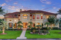 a large home with palm trees and landscaping in front of it at dusk or dawn