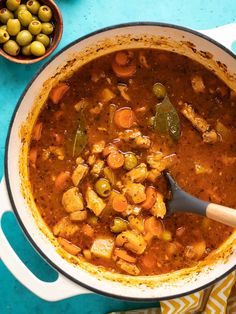 a large pot filled with soup next to olives