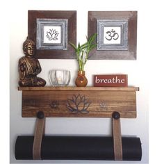 there is a buddha statue on top of a shelf with two framed pictures above it