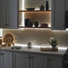 a kitchen with white cabinets and lights on the back wall, along with an oven