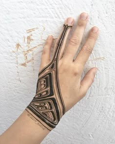 a person's hand with a tattoo on it and a white wall in the background