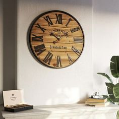 a large wooden clock mounted to the side of a wall next to a potted plant