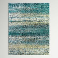 an abstract rug with blue, green and yellow colors on the floor in front of a white wall