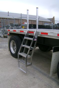 there is a ladder attached to the back of a large truck with no wheels on it