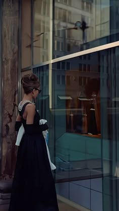 a woman in a black dress is walking down the street