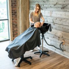 a woman is getting her hair cut by a barber in front of a wooden wall