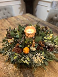 a candle is sitting on top of a table with greenery and other things around it