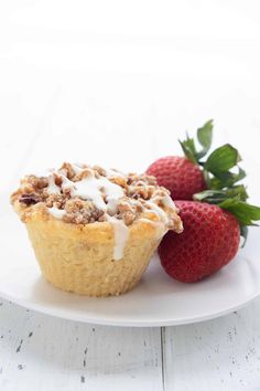 a muffin on a plate next to strawberries and a cup of coffee