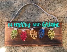 a wooden sign that says be merry and bright with string lights hanging from the strings