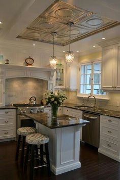 a kitchen with white cabinets and an island in front of the sink, stove top oven and dishwasher