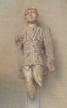 a wooden statue of a man wearing a suit and holding a cane in his right hand