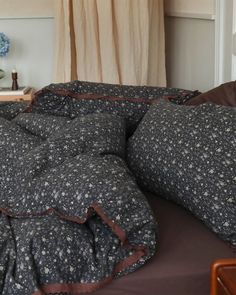 a bed with black and white comforter on top of it next to a window