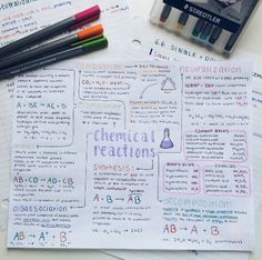 some writing paper with markers and pens on top of it next to two notebooks that have chemical reactions written on them