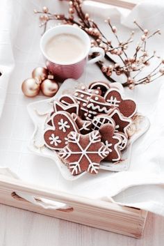 some cookies are sitting on a plate next to a cup of coffee and christmas decorations