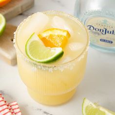 a margarita cocktail garnished with an orange slice and lime on a marble counter