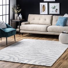 a living room with black walls and white rugs on the wooden floored floor