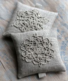 two decorative pillows sitting on top of a bed next to each other with crocheted designs