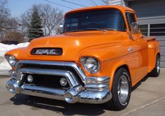 an orange truck parked in a parking lot next to a building with snow on the ground