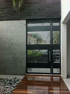 the front door to a modern house with wood flooring and black shuttered doors