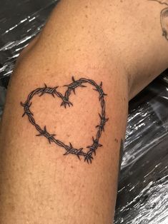 a heart shaped barbed wire tattoo on the arm