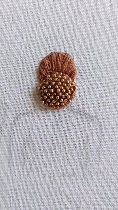 a piece of cloth with some beads on it and a pin in the shape of a flower