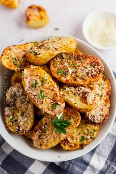 a white bowl filled with fried potatoes covered in parmesan cheese and seasoning