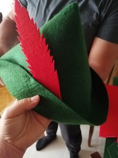 a person is holding a green and red hat