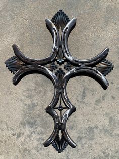 a metal cross on the ground in front of a cement wall