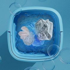 two pairs of gloves in a blue container filled with soapy water and bubble bubbles