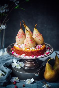 three pears on top of a cake with sprinkles and white flowers