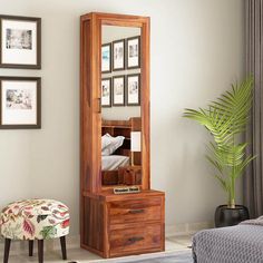 a mirror sitting on top of a wooden dresser next to a plant in a living room