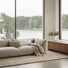 a living room with large windows and a couch in front of the window overlooking water